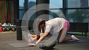 Sporty woman in activewear doing stretching exercise in gym