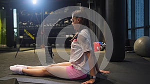 Sporty woman in activewear doing stretching exercise in gym