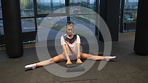 Sporty woman in activewear doing stretching exercise in gym