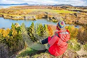 Sporty woman admires the lake Myvatn in Northern Iceland. Quiet autumn landscape