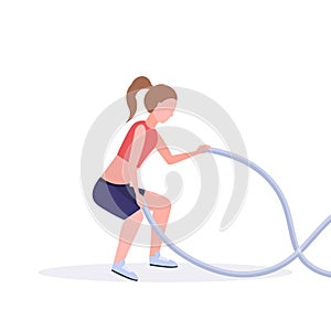 Sporty woman doing crossfit exercises with battle rope girl training in gym cardio workout healthy lifestyle concept