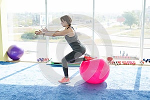 Sporty woman doing exercises with fit ball in gym. Concept: lifestyle, fitness, aerobics and health