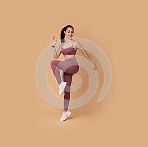 Sporty Woman Doing High Knees Exercise Isolated On Pink Background