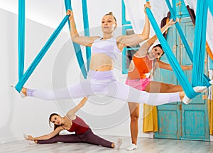 Sporty woman doing split on hanging hammocks during aerial yoga training