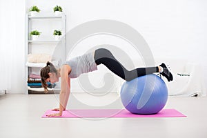 Sporty woman doing stretching fitness exercise on ball