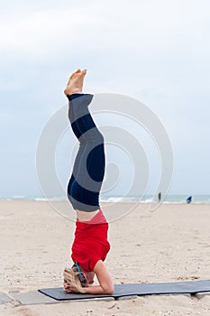 Sporty woman doing Supported Headstand, yoga asana Sirsasana, Shirshasana, Sirshasana, Headstand on sea background