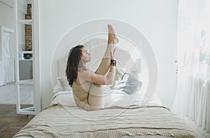 A sporty woman doing yoga, performing the Paripurna Navasana exercise, balance pose, at home or in a yoga studio with