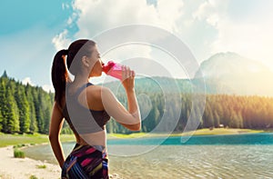 Sporty woman drink water, training on lake shore