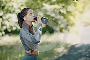 Sporty woman drinking bottled water in park