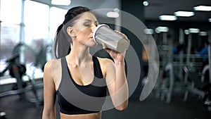 Sporty woman drinking protein shake after workout, muscle gain nutrition, health