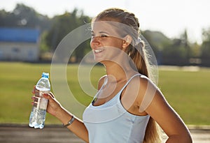 Sporty woman drinking water against the stadium.