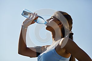 Sporty woman drinking water against the stadium.