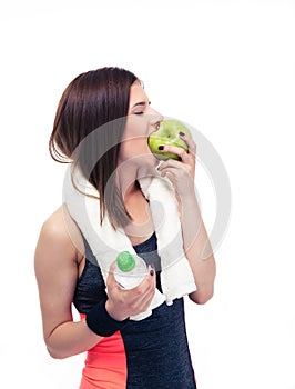 Sporty woman eating apple and holding bottle with water