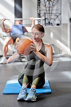 Sporty woman exercising with ball on fitness mat at the gym.