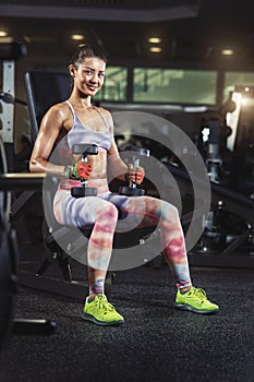 sporty woman exercising in gym with dumbbells