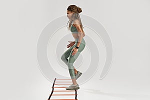 Sporty woman. Full length shot of young sportive mixed race woman in sportswear training on agility ladder drill
