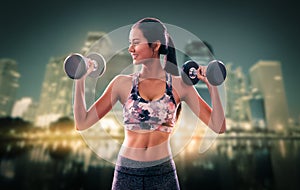 Sporty woman holding fitness dumbbell with smile working out with modern night city in the background