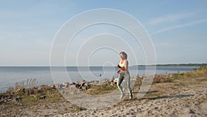 Sporty woman jogging along sea coast with dog