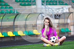 Sporty woman keep football ball between legs