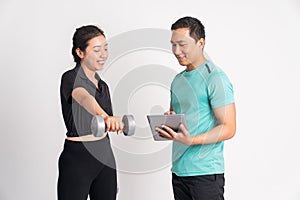 sporty woman lifting dumbbells and man guiding using a pad