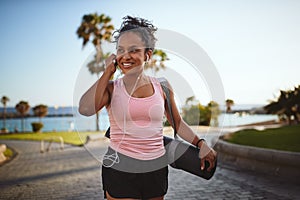 Sporty woman listening to music while carrying her yoga mat