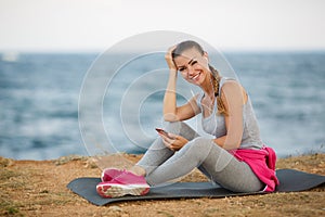 Sporty woman listening to music sitting on the beach