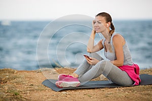 Sporty woman listening to music sitting on the beach