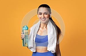 Sporty woman looking at camera holding water bottle