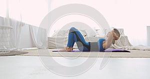 Sporty woman is making abdominal exercises crunches on floor at home, side view.