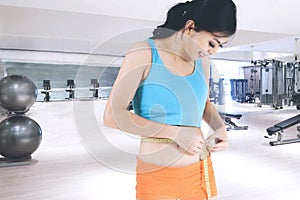 Sporty woman measuring her slim waist