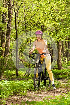 Sporty woman with mountain bike on woodland trail