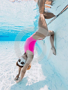 Sporty woman in pink sexy swimwear posing underwater in pool