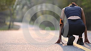 Sporty woman preparing for a run at sunset in park.