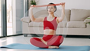 Sporty woman in red costume doing exercises with the fitness band