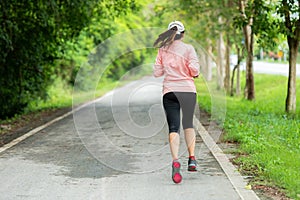 Sporty Woman runner running through the road. Workout in a Park. Outdoor Workout in a Park.