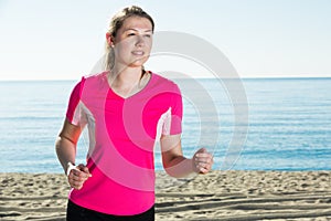 Sporty woman running on ocean beach