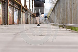 Sporty woman running on an old boardwalk bridge