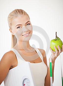 Sporty woman with scale, apple and measuring tape