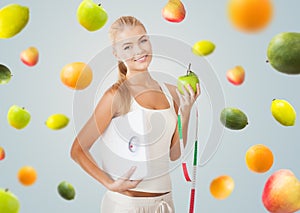 Sporty woman with scale, apple and measuring tape