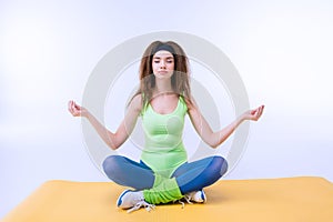 Sporty woman sititng in lotus pose on mat