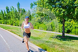 Sporty woman in sportswear trail running on the road. Athlete girl is jogging in the park