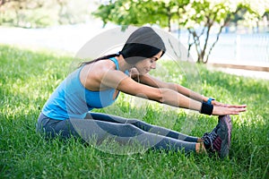 Sporty woman stretching on green grass
