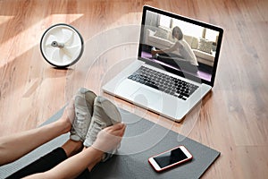 Sporty woman stretching at home while watching online classes