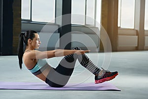 Sporty woman with strong body making exercises on gym floor.