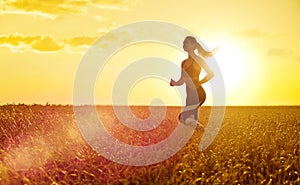 Sporty woman at sunset in wheat field