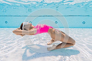 Sporty woman in swimwear posing underwater in swimming pool