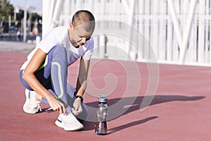 sporty woman tying running shoes before workout