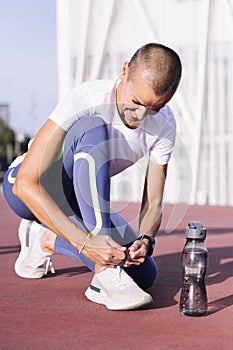 sporty woman tying running shoes before workout