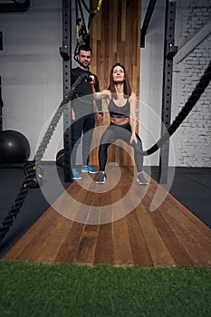 Sporty woman using fitness ropes in gym