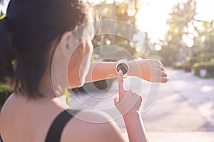 Sporty woman using smart watch for running and checking device at outdoor during sunrise in the morning